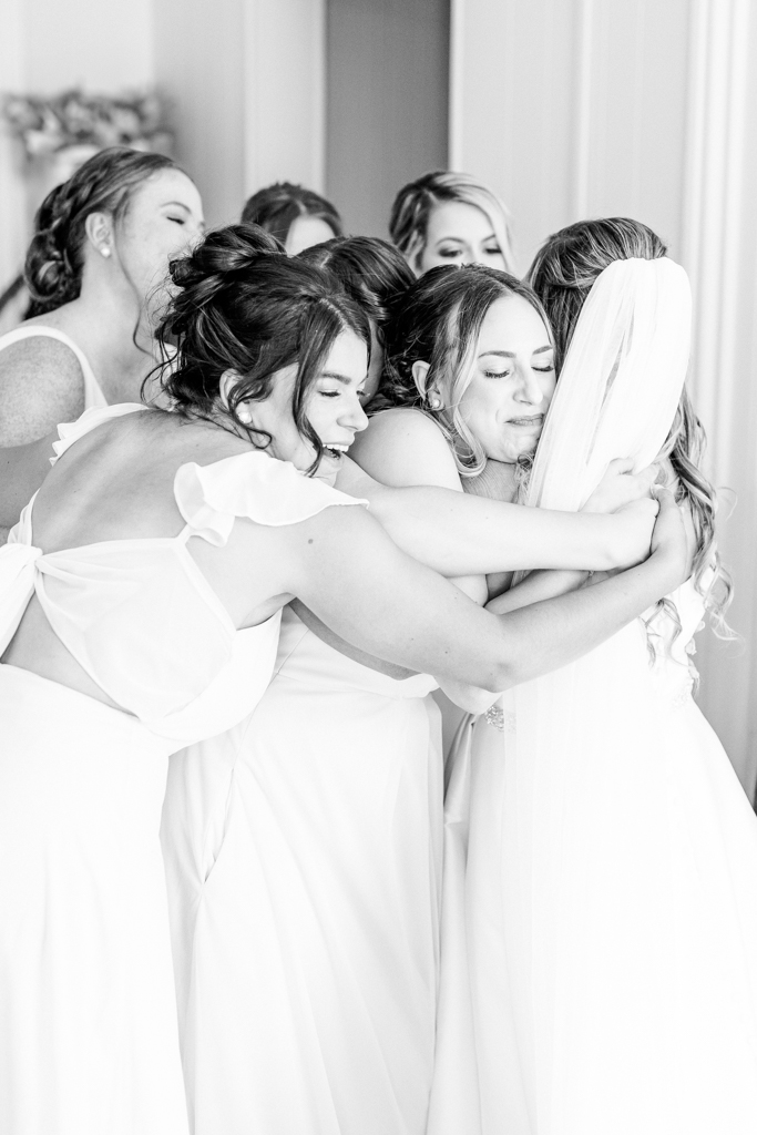 Bride embracing bridesmaids in bridal suite at Mansion at Valley Country Club