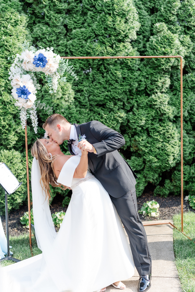 Bride and groom's first kiss during their wedding ceremony on the lawn at the Mansion at Valley Country Club in Towson, MD
