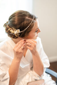 Baltimore bride puts on her earrings in her bridal suite before getting into her dress