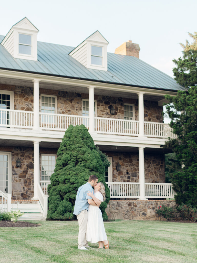 Casey and Giovanni sharing a kiss in front of the historic house at Bortner Valley during their engagement session