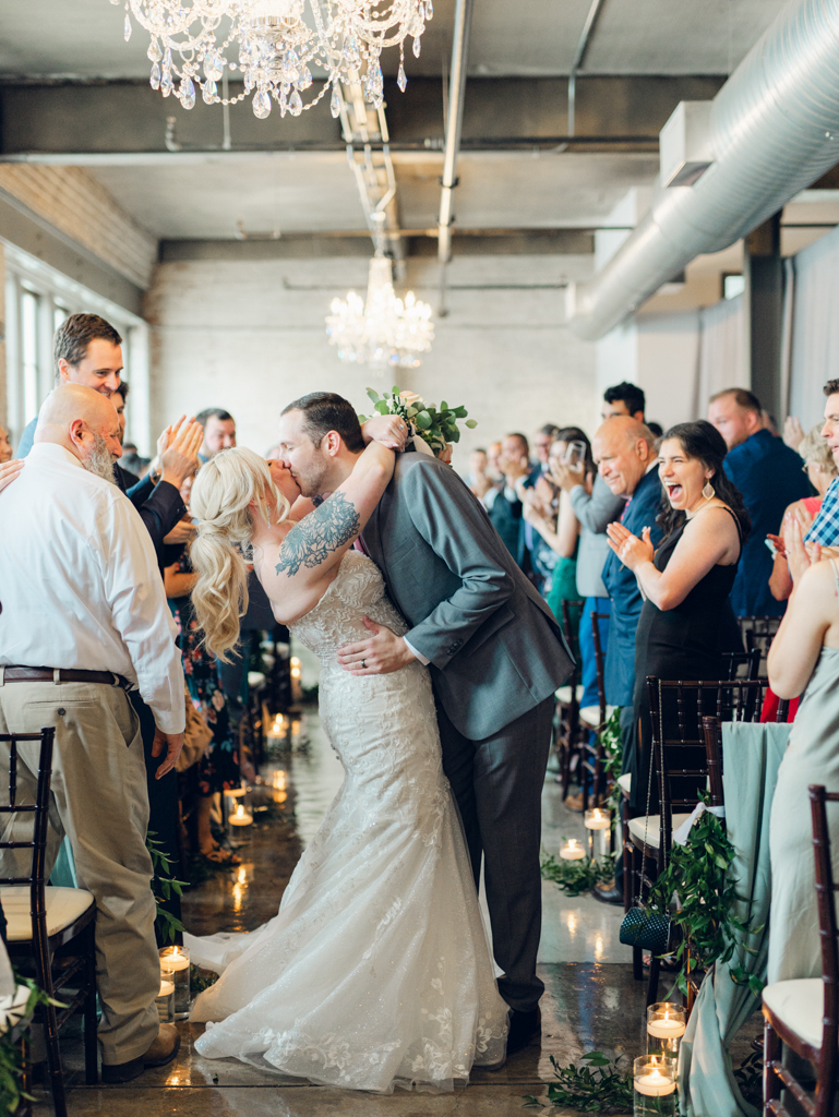 Amanda and Corey sharing a kiss during their recessional after being pronounced husband and wife on their wedding day at The Bond Events. 