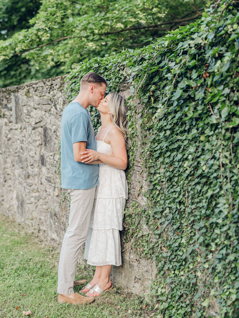 Victoria and Jacob sharing a kiss on the ivy wall during their engagement session at Cold Saturday Farm.