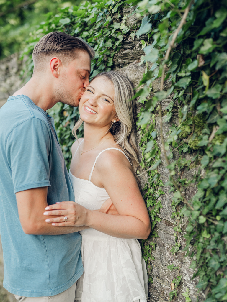 Cold Saturday Farm engagement session with Jacob kissing Victoria's cheek near the ivy wall