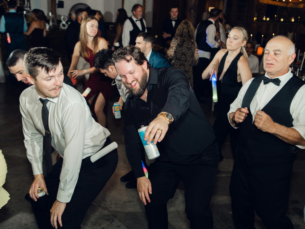 groom and guests dancing at wedding reception with glow sticks at The Hummingbird Chateau