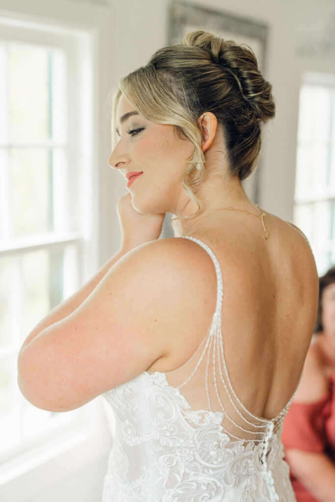 bride putting on her earrings on her wedding day at The Hummingbird Chateau