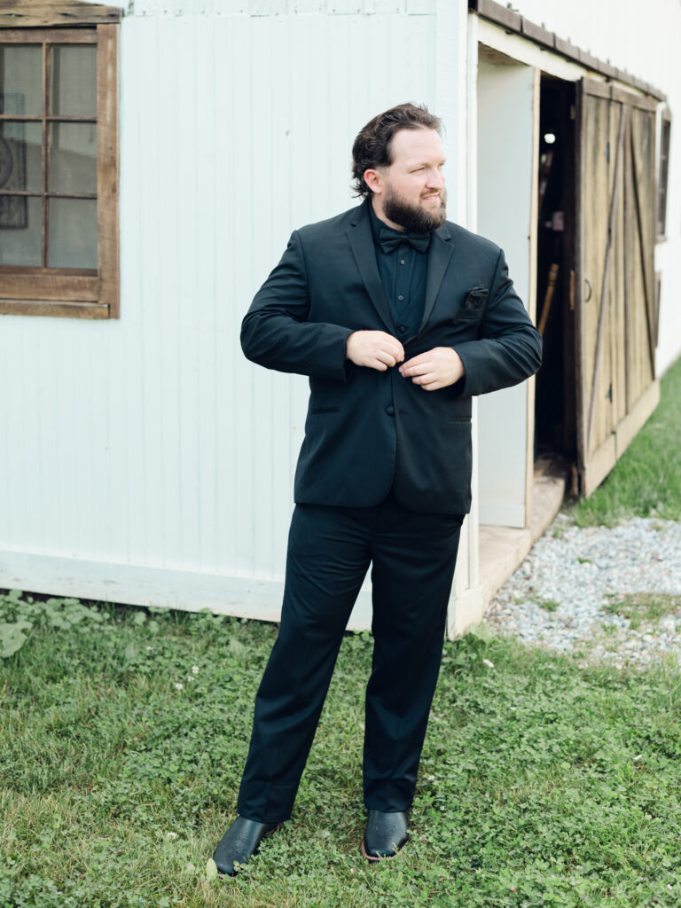 Jason's portraits outside the barn at The Hummingbird Chateau on his wedding day. Looking into the field while buttoning his jacket.