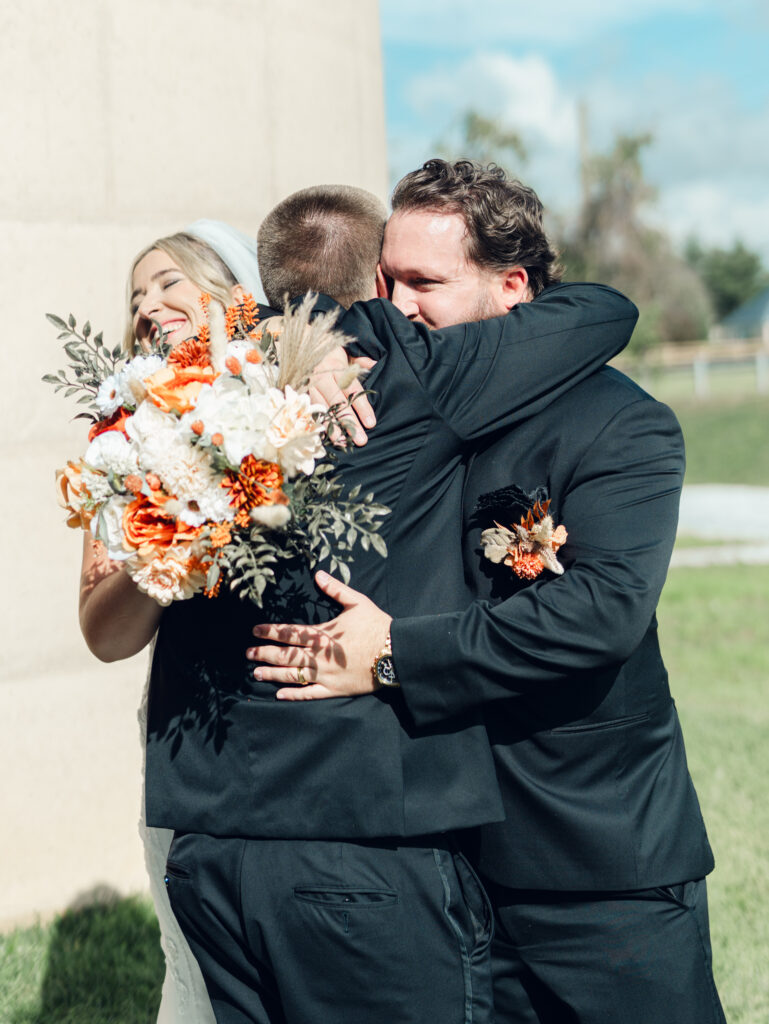 Bride and groom hugging friend after wedding ceremony