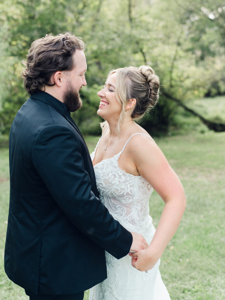 Bride and groom smiling and laughing with each other at The Hummingbird Chateau on their wedding day