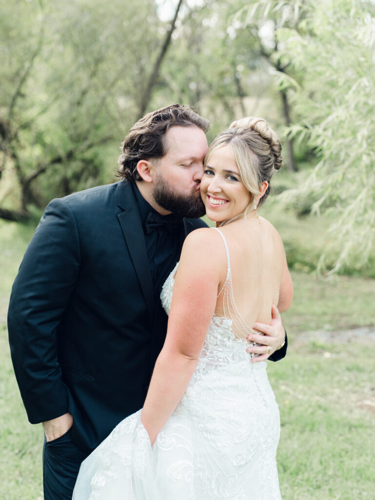 groom kissing bride on cheek at their The Hummingbird Chateau wedding day