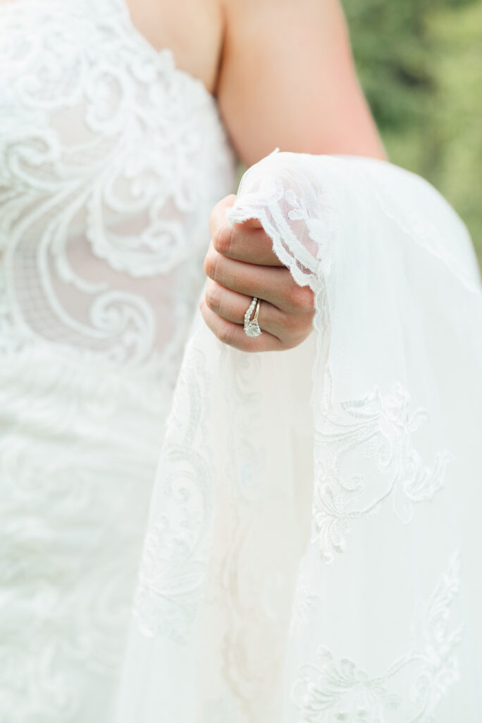 bride holding her bridal gown train showing off her wedding ring and engagement ring. 