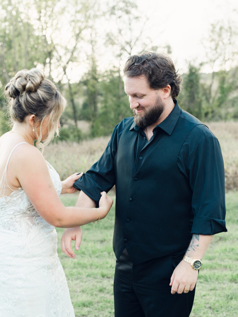 bride rolling up her groom's sleeves on their wedding day