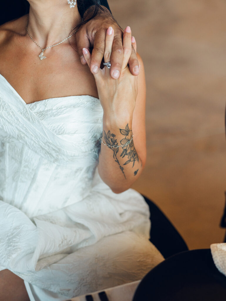 bride holding groom's hand showcasing wedding gown and wedding rings