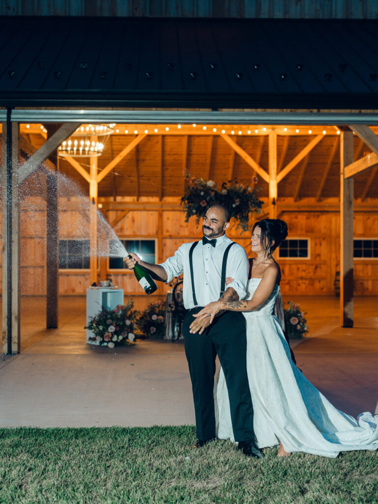 bride and groom popping champagne outside of their wedding venue Bortner Valley in Hampstead, MD