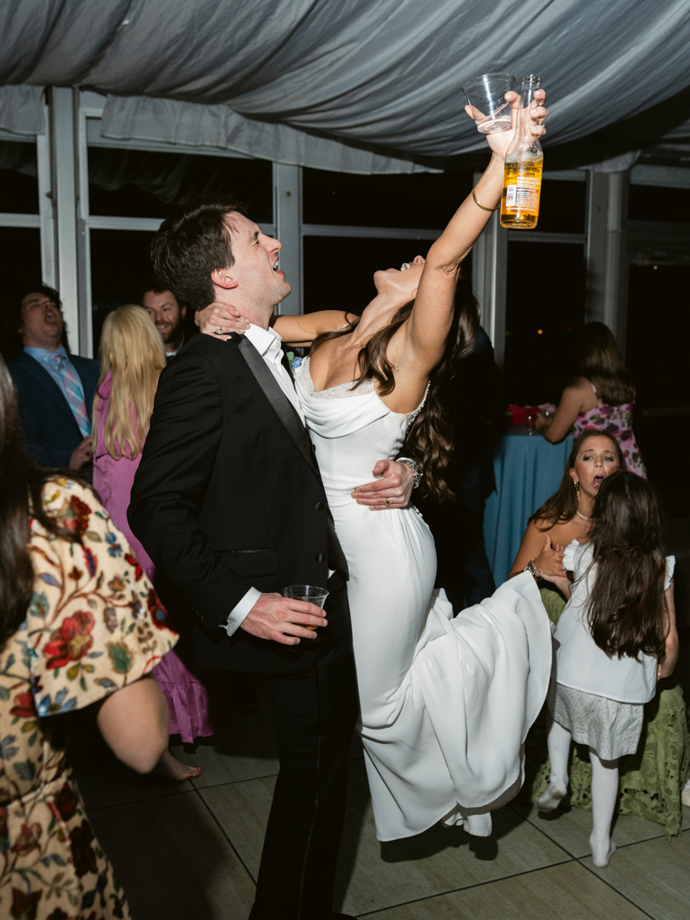 groom picking up bride while she celebrates during their wedding reception at Silver Swan Bayside by Baltimore wedding photographer