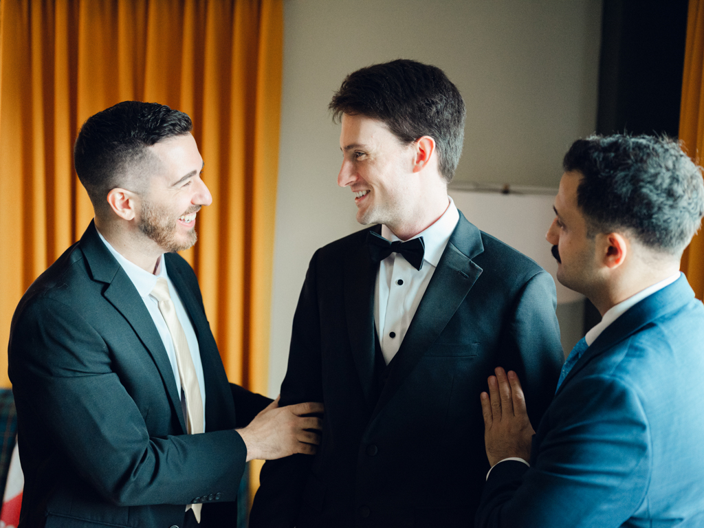 groom and his groomsmen helping him get ready before his first look at the Graduate Hotel Annapolis