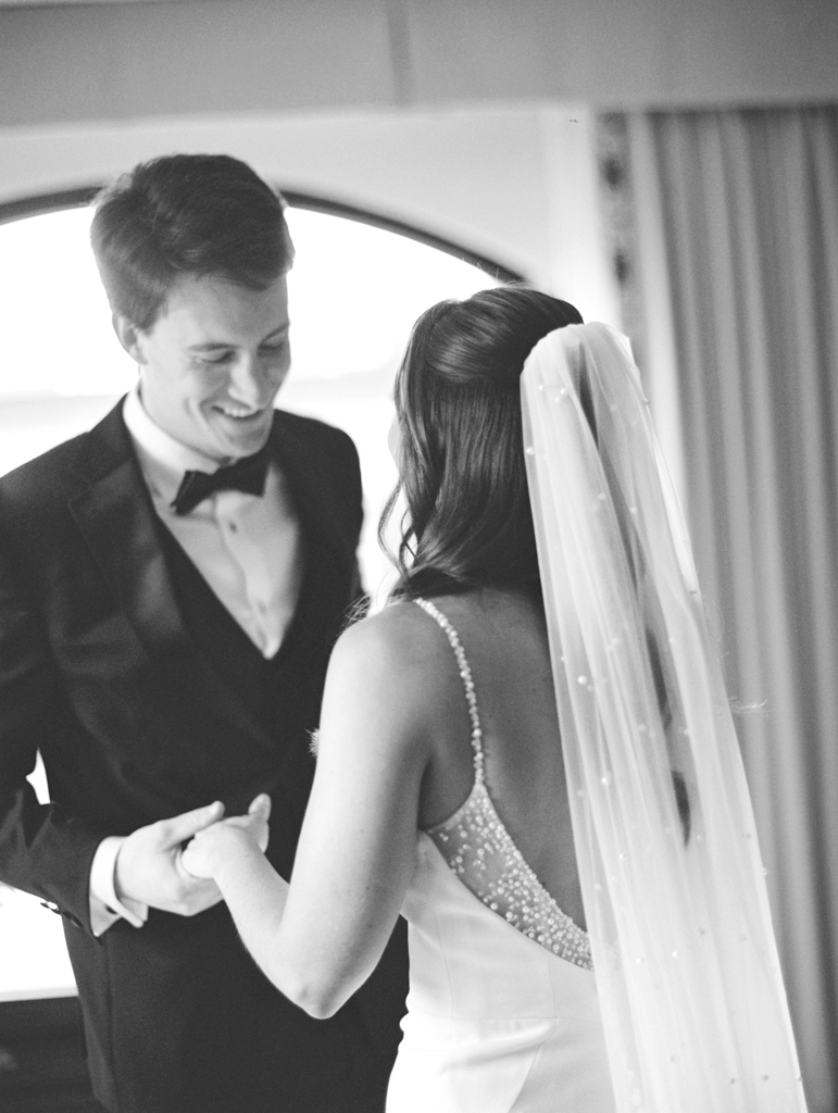 Bride and groom smiling with each other during their first look at the Graduate Hotel Annapolis