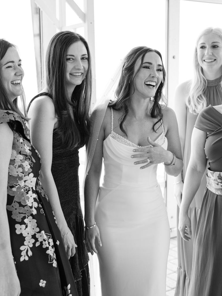 bride laughing with her bridesmaids on her wedding day