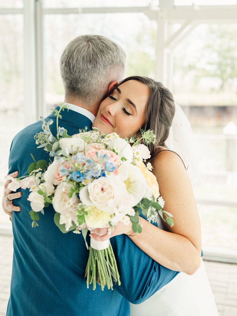 bride hugging stepdad during their informal first look prior to her wedding ceremony at Silver Swan Bayside