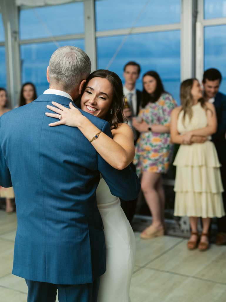 Bride hugging her stepdad during their parent dance on her wedding day at Silver Swan Bayside