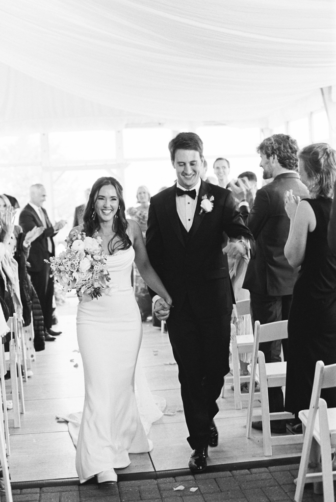 Bride and groom walking back up the aisle at Silver Swan bayside on their wedding day taken by film wedding photographer
