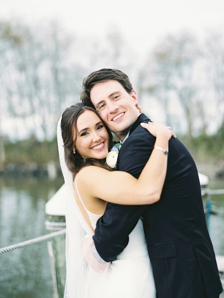 Bride and groom embracing and smiling at the camera on their wedding day taken by film wedding photographer