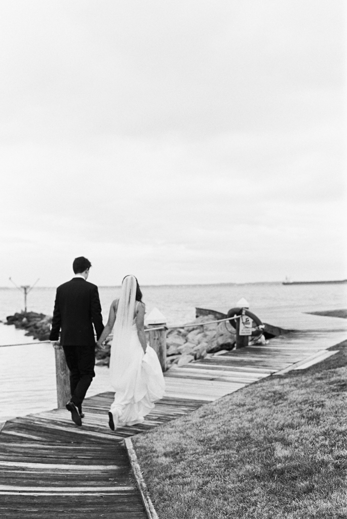 Bride and groom walking down the boardwalk at Silver Swan bayside on their wedding day taken by film wedding photographer