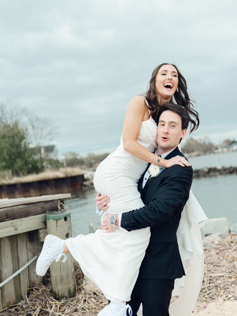 Bride and groom having a playful moment on the beach at Silver Swan bayside on their wedding day taken by film wedding photographer