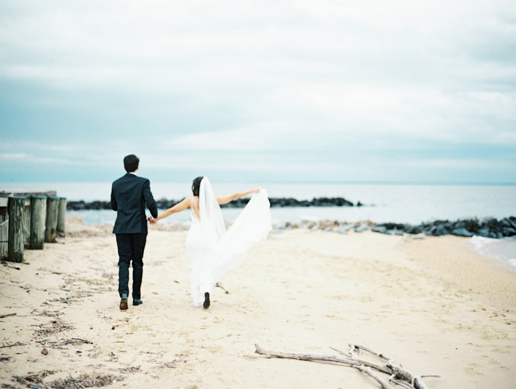 Bride and groom running down the beach at Silver Swan bayside on their wedding day taken by film wedding photographer