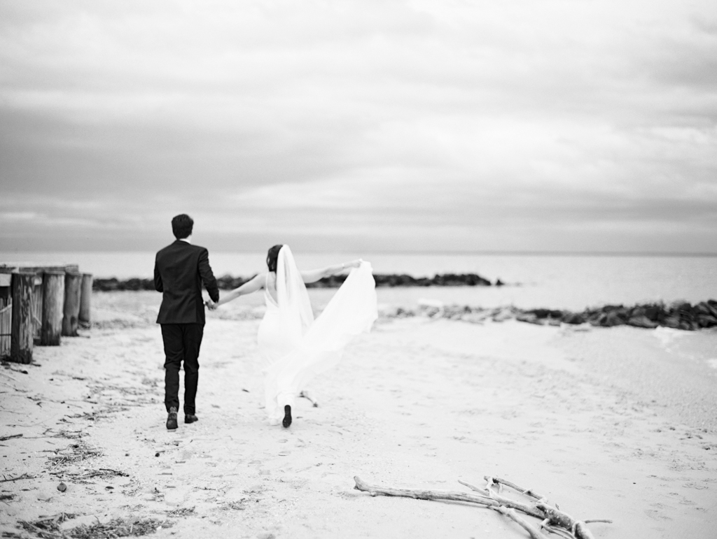 Bride and groom running down the beach at Silver Swan bayside on their wedding day