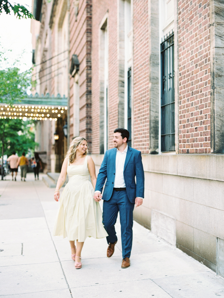 couple smiling walking down the sidewalk in Mount Vernon Baltimore by Baltimore wedding photographer