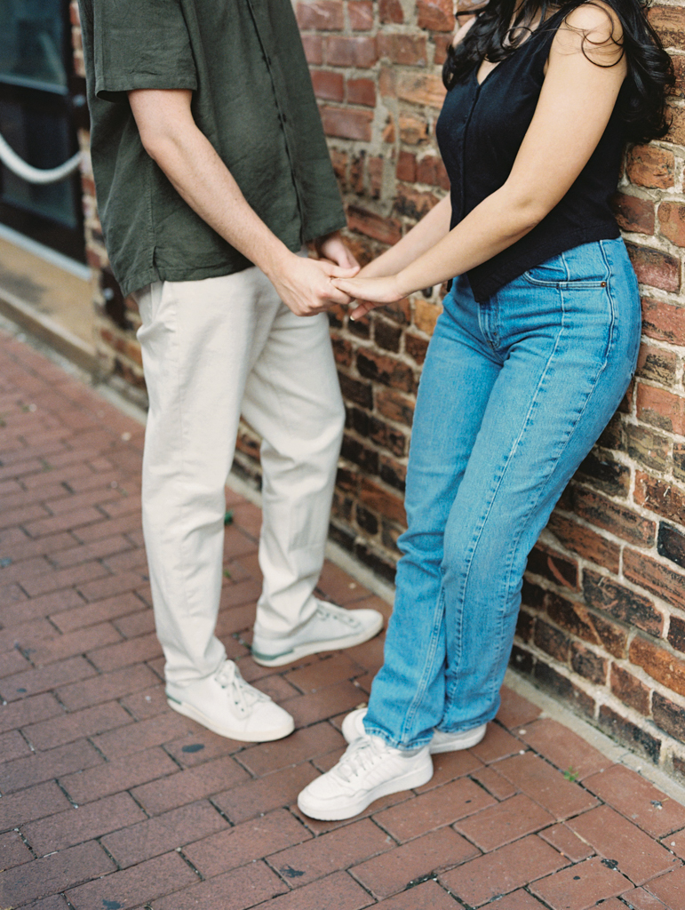 couple holding hands during their engagements session in Blagden alley by dc film wedding photographer